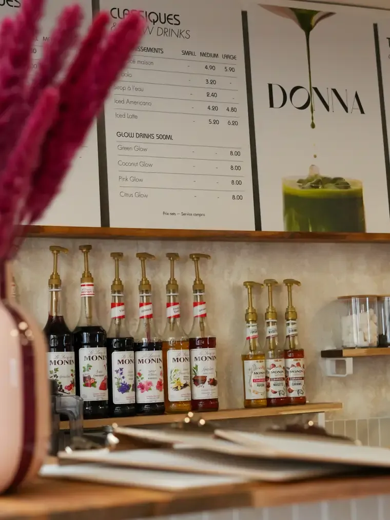 Le comptoir du café : la carte au mur et la rangée de sirops