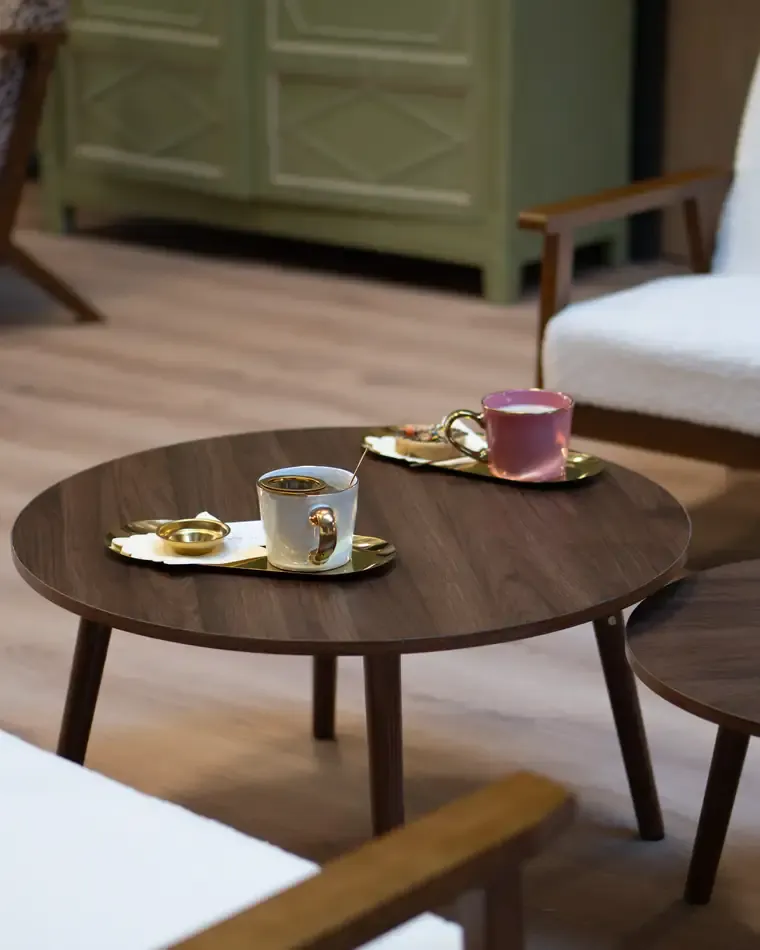 Deux tasses sur une table basse en bois, entre les fauteuils du salon du café